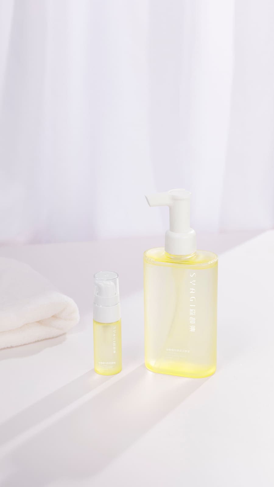 Two glass bottles of cleansing oil on a clean white surface.