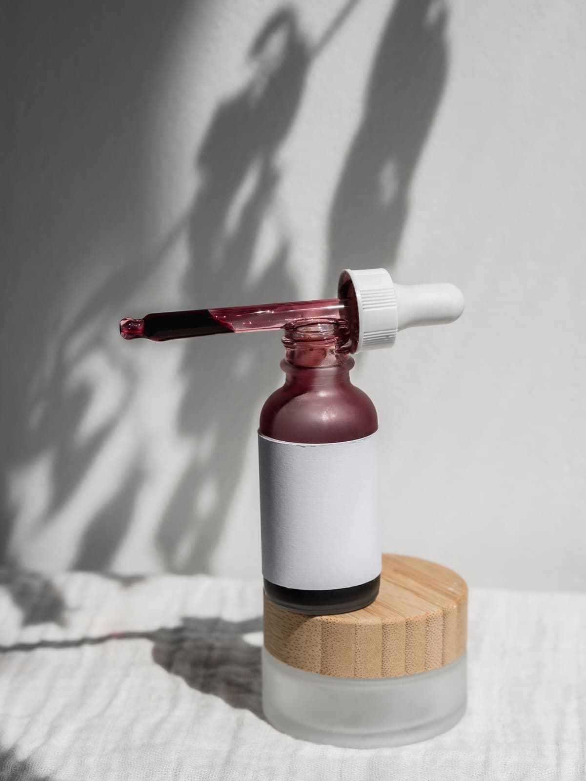 A serum bottle with dropper casting a soft shadow.