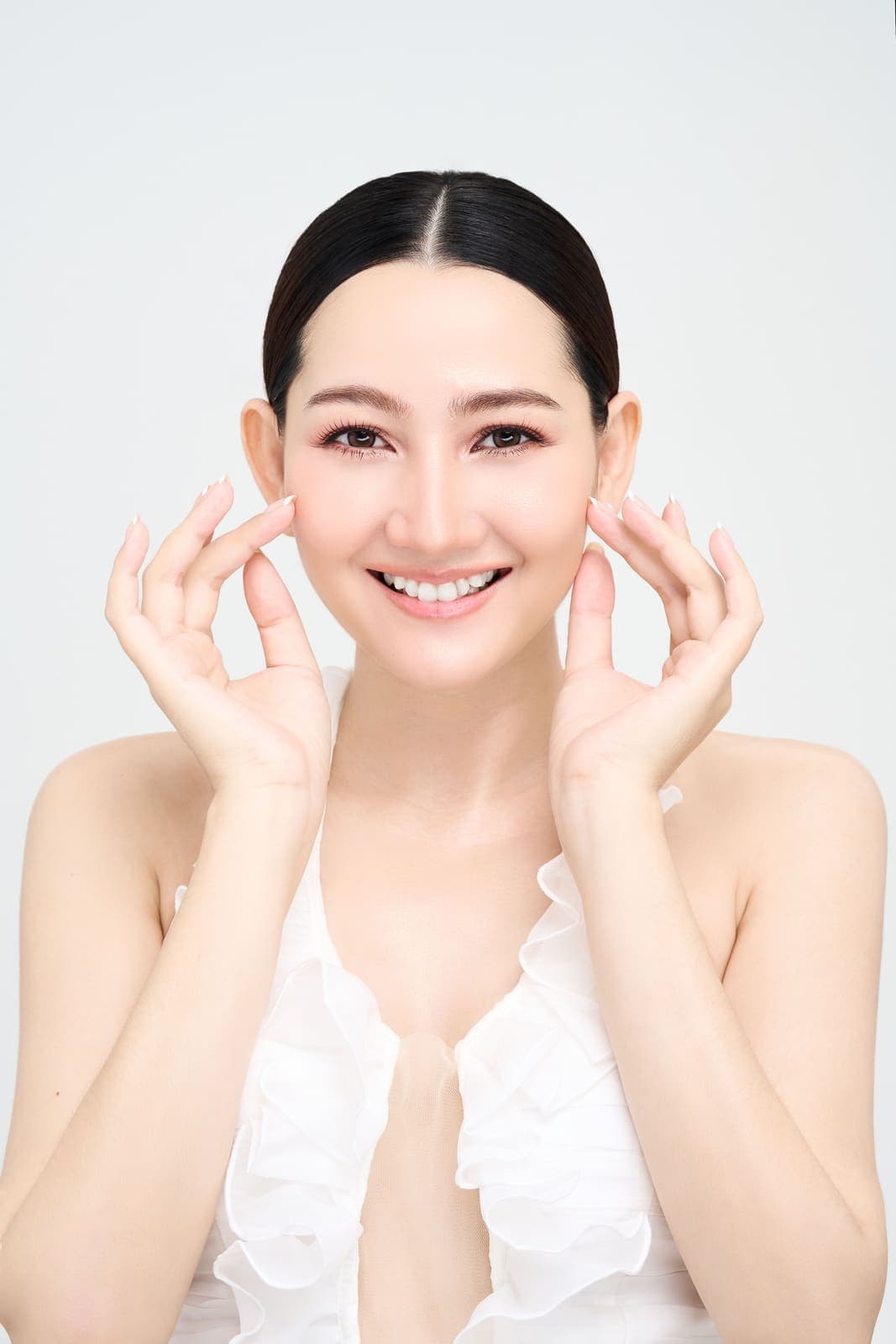 A woman with a radiant, healthy complexion applying skincare.