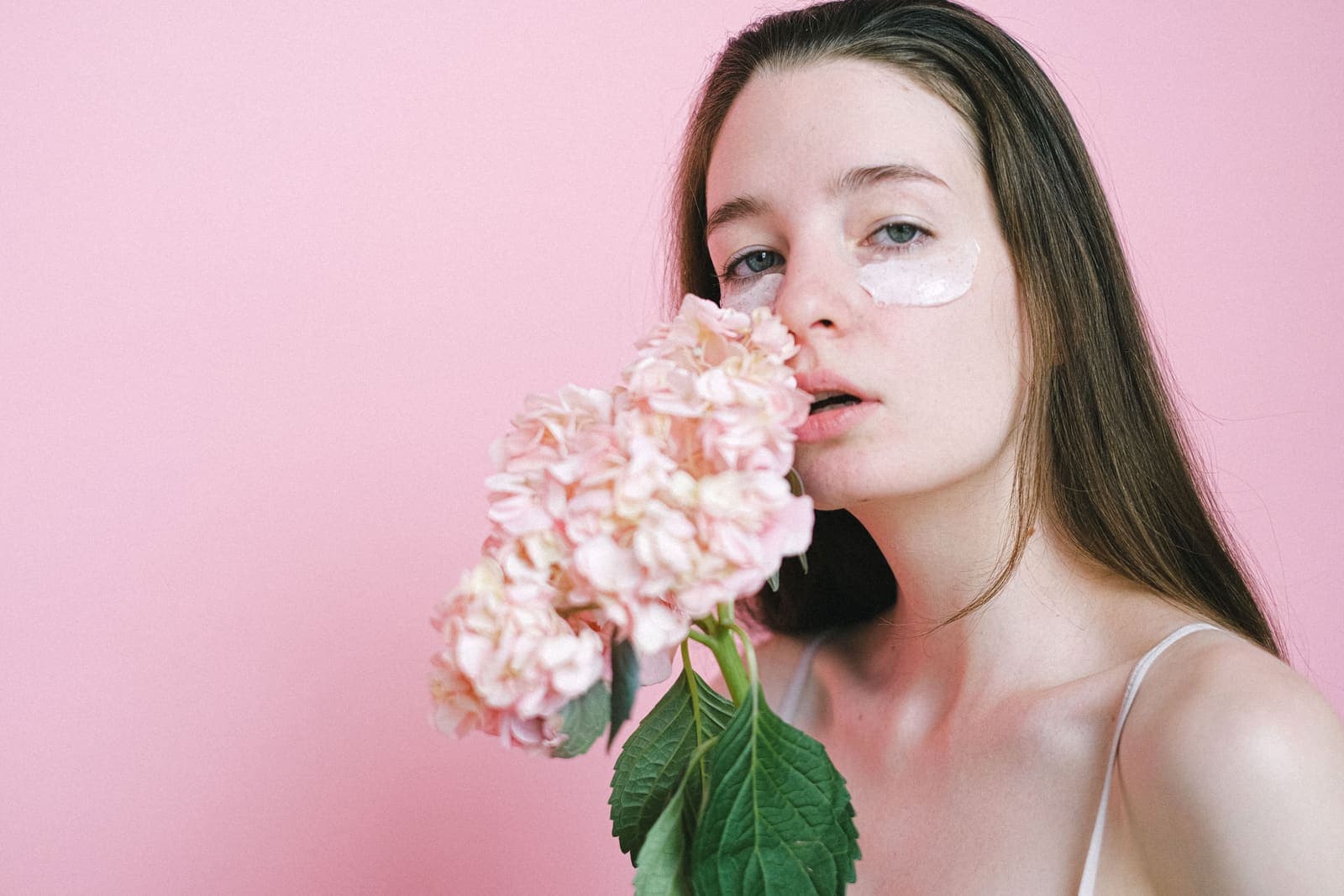 A gentle skincare moment set against a soft pink background.