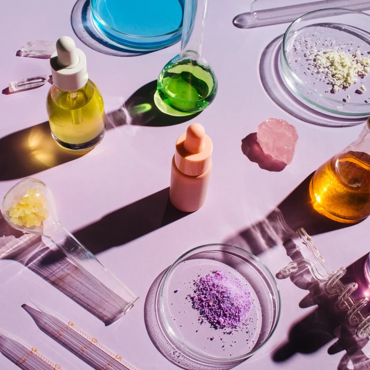 Skincare ingredients and lab glassware arranged on a lilac surface
